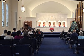 People sitting in silent meditation in front of an altar with photos of SRF gurus