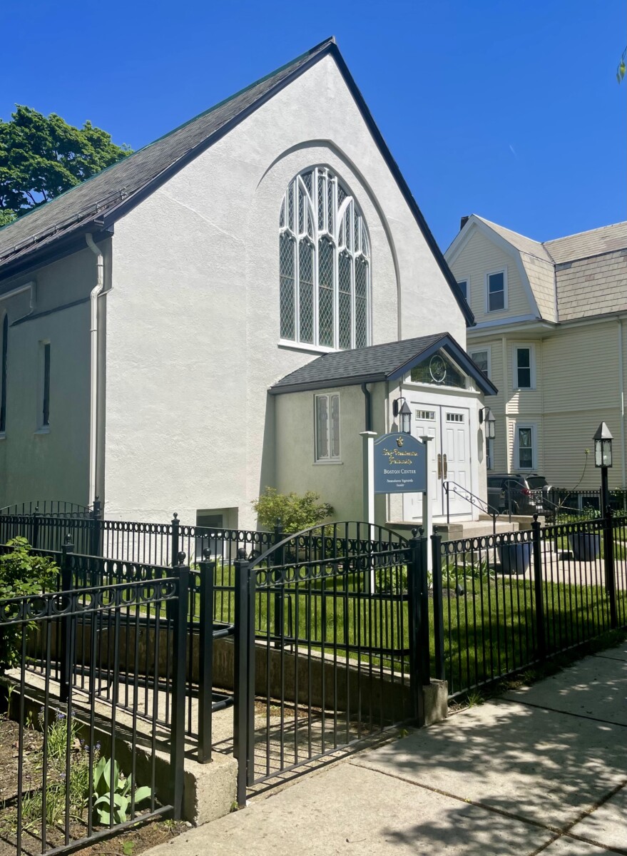 View of white church and yard with black iron fence around it